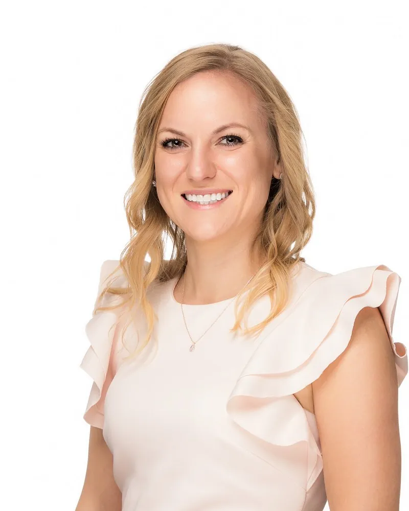 Professional individual headshot of a woman in a pink ruffled top photographed on a white studio backdrop