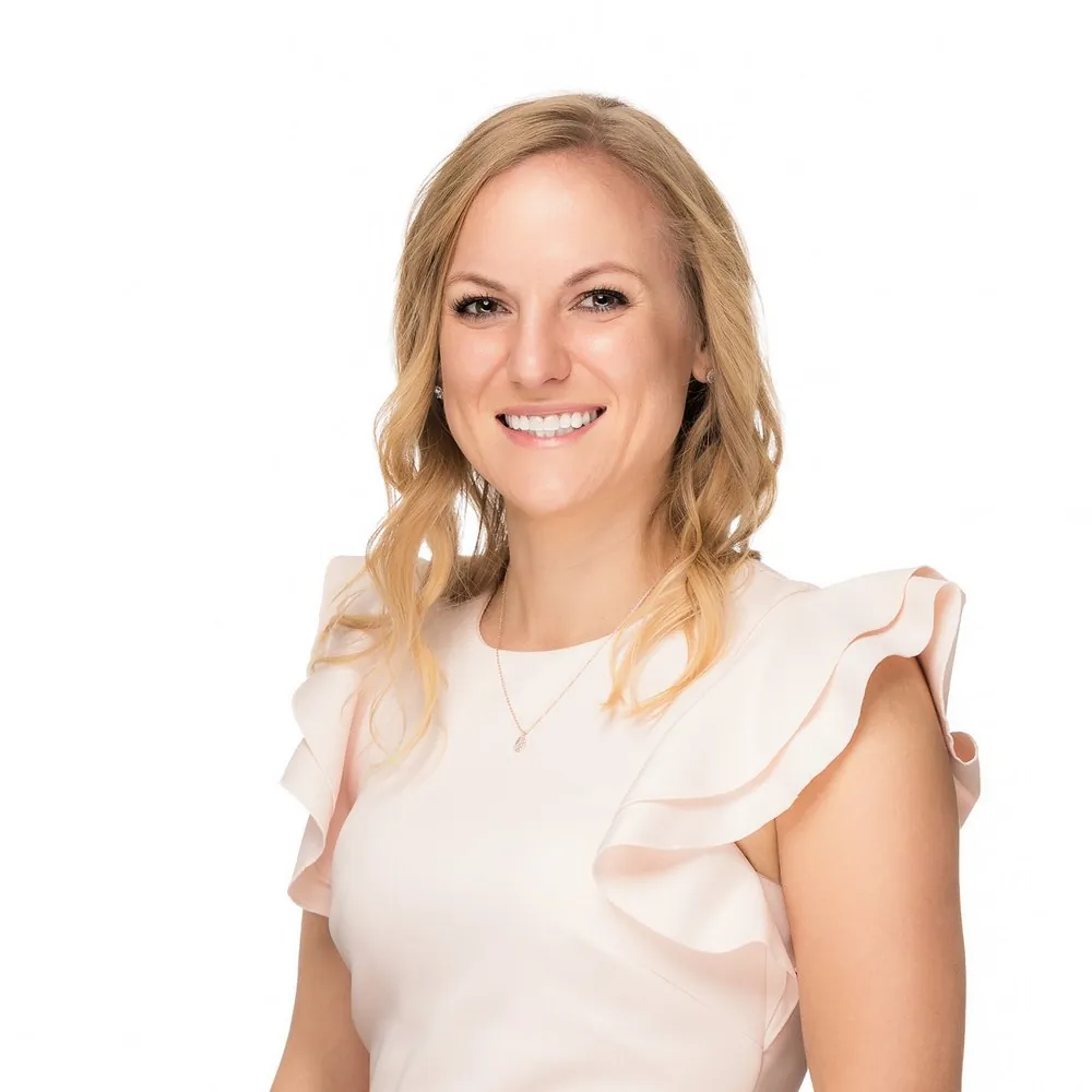 Headshot of a blonde woman in a pink ruffled top on a white backdrop